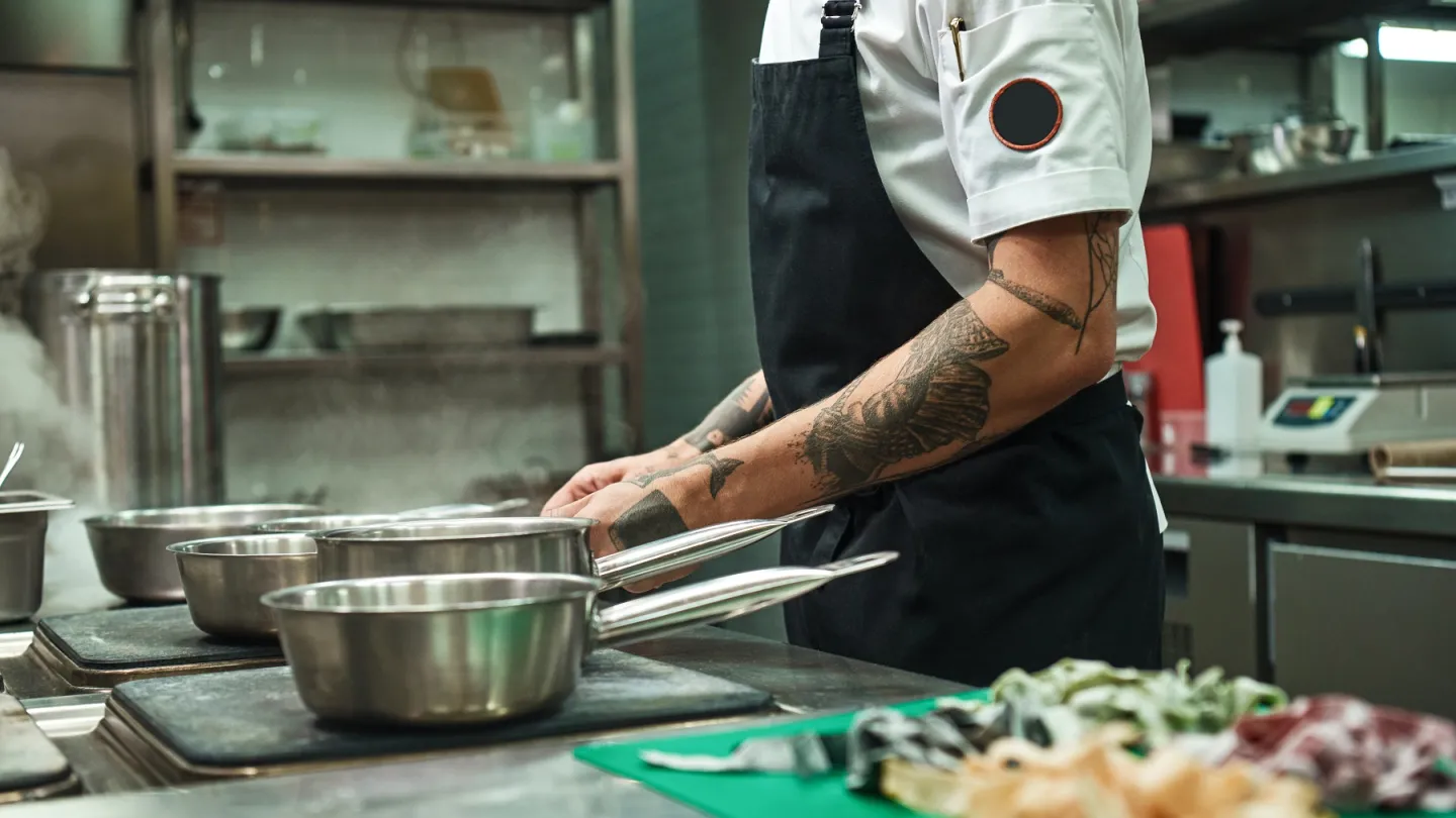 Kock som lagar mat i kök. 