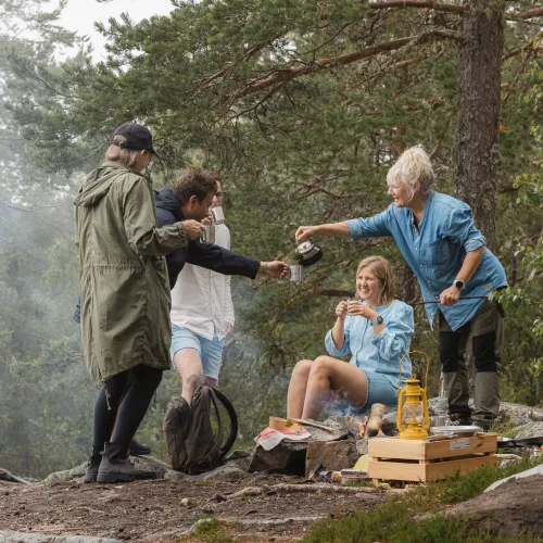 Grupp personer lagar mat i skogen.